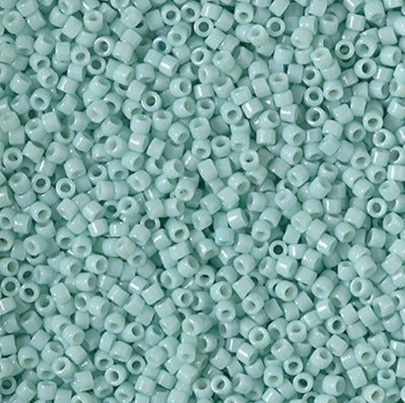A close-up pile of small cylindrical seed beads in a pale mint green color, filling the entire frame.