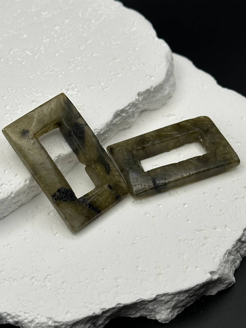 Two rectangular labradorite beads on a textured white surface