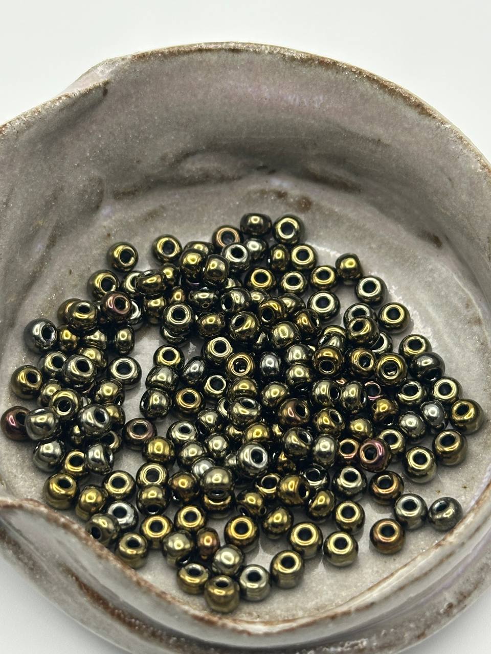 Small metallic beads in a ceramic dish on a white background