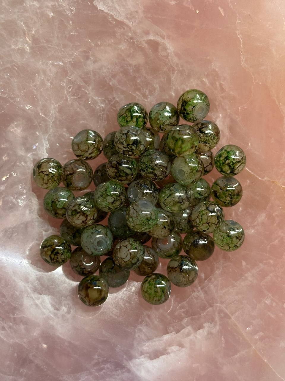 Green picasso beads on a pinkish stone surface