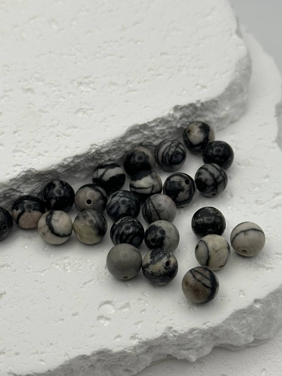 Black and white marbled beads on a textured white surface
