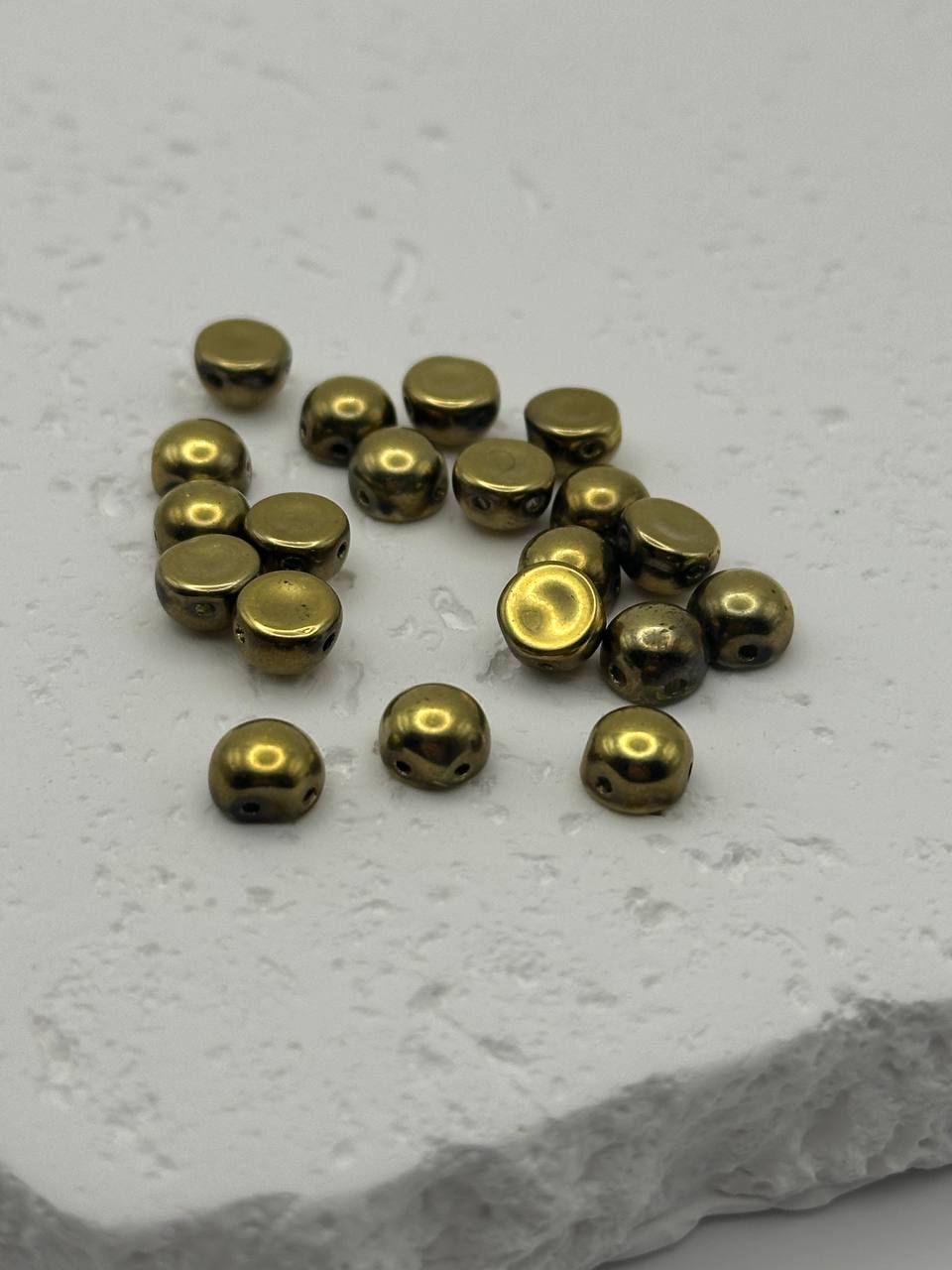 Gold colored cabochons on a textured white surface