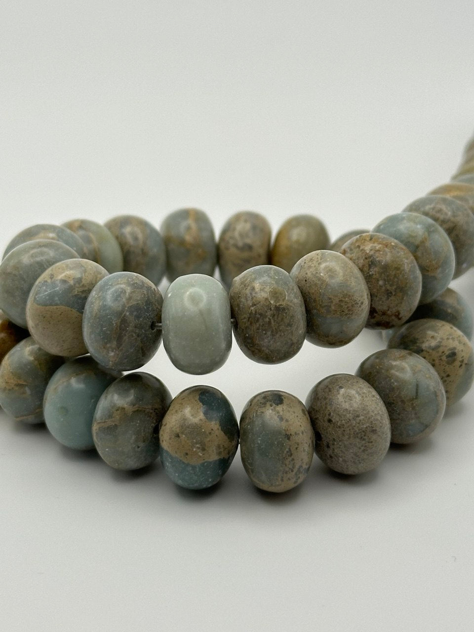 grey blue sandy picasso stone rondelle beads on white surface