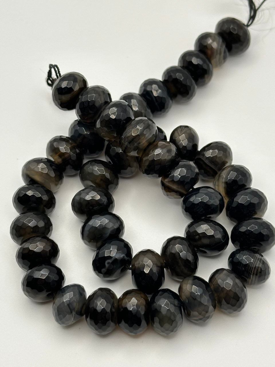String of black faceted eye agate beads on a white background
