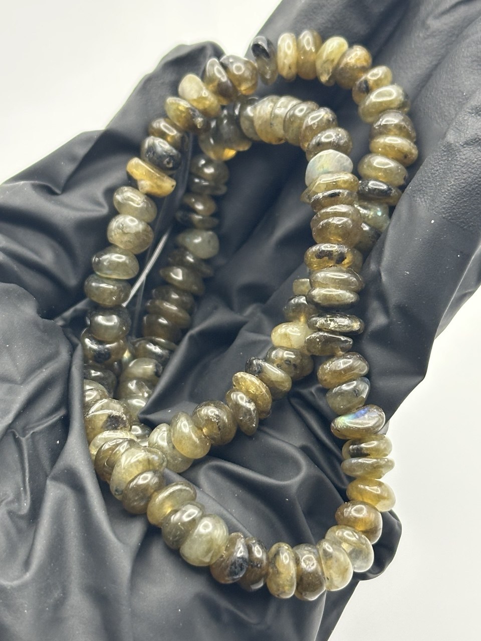 Closeup on a string of labradorite inclusion smoky quartz beads on a black background
