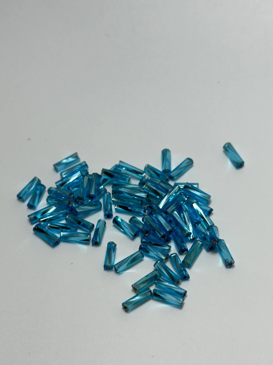 A small pile of twisted bugle beads in blue color