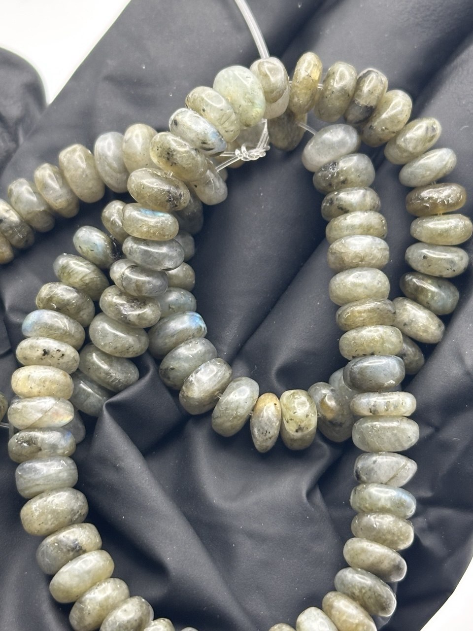 Close up of labradorite rondelle beads with iridescence on a black background