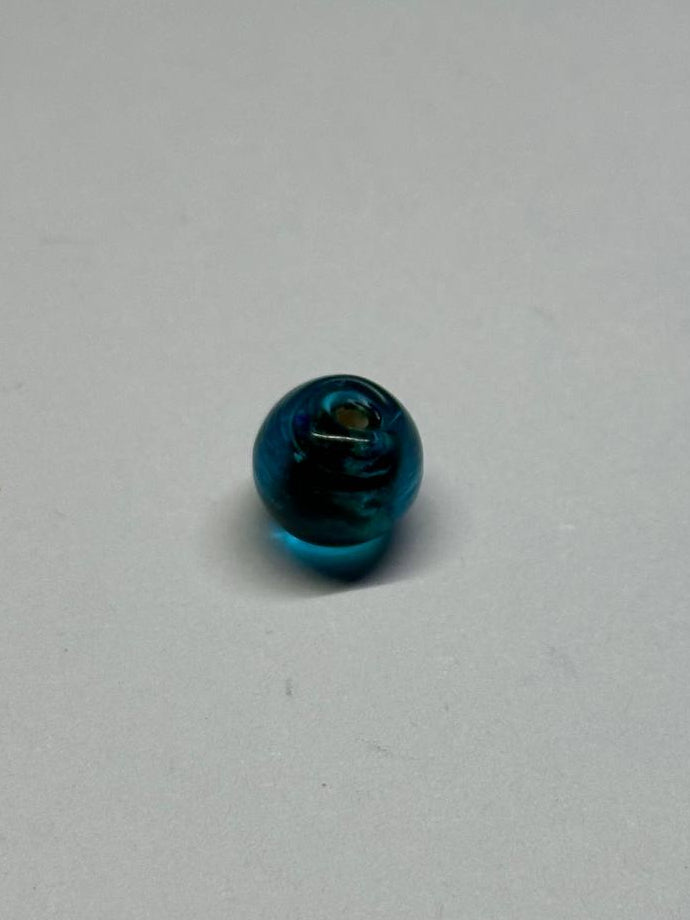 Small blue glass bead on a gray background