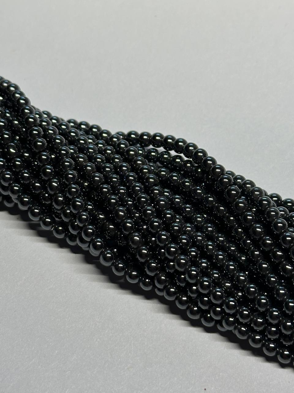 String of black hematite beads on a light gray background