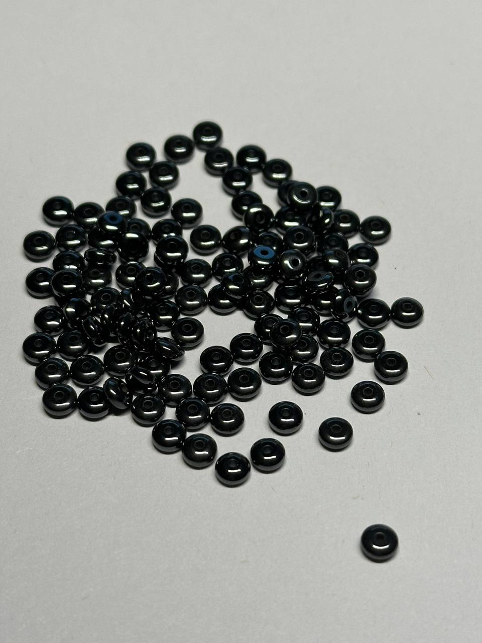 Small black hemalyke beads scattered on a gray surface