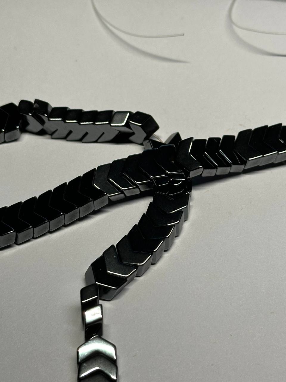 Black chevron hemalyke or hematite beads on a light gray background