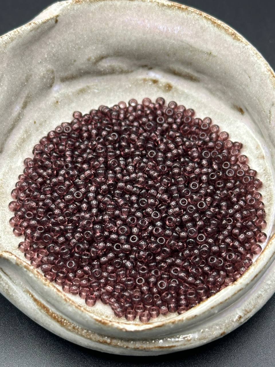 Close-up of small purple beads in a ceramic container