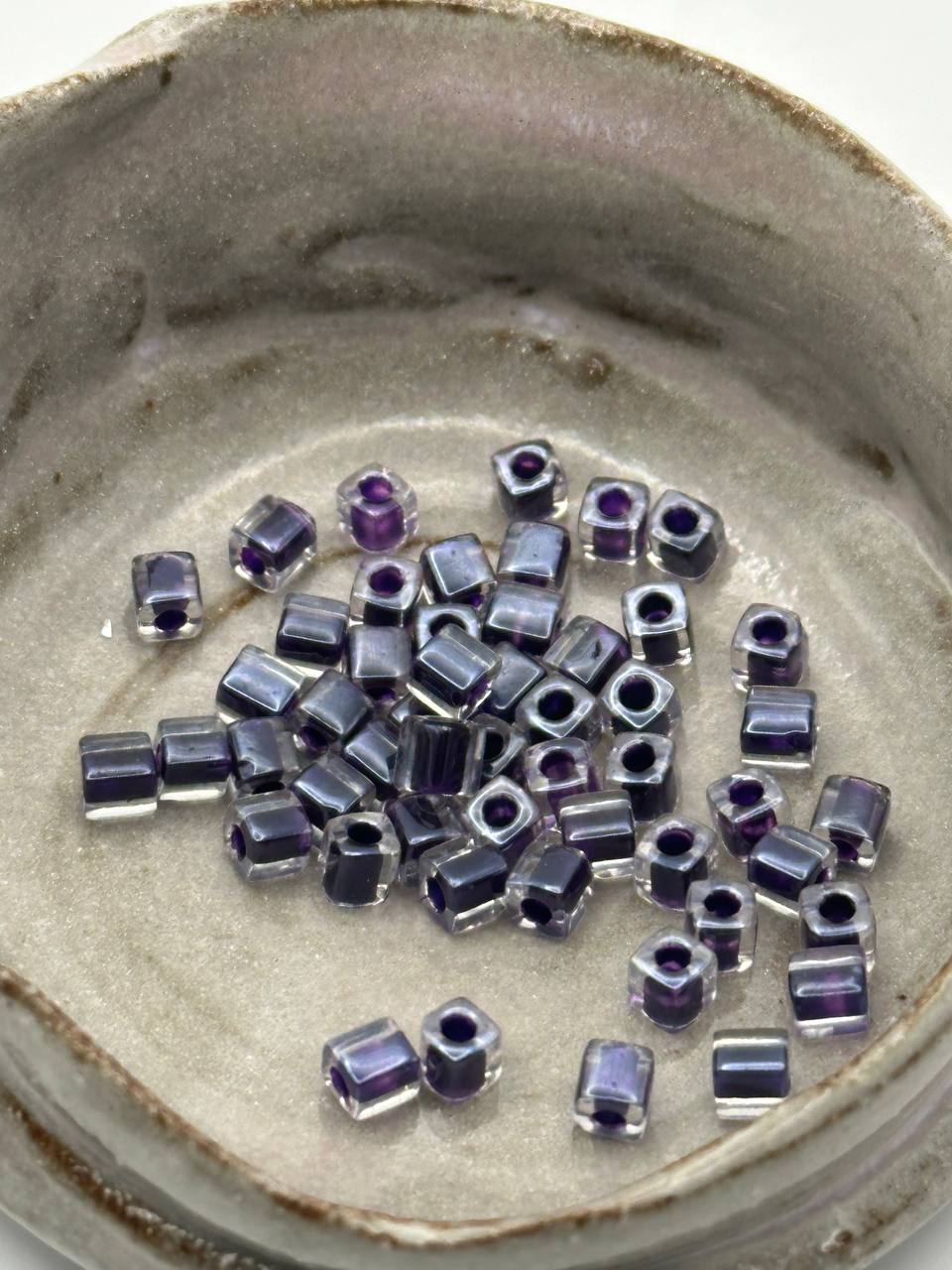 Small purple beads on a textured beige surface