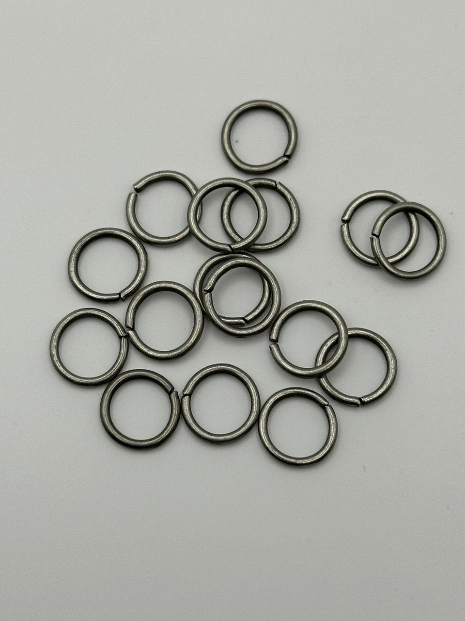 Collection of silver metal jump rings on a gray background