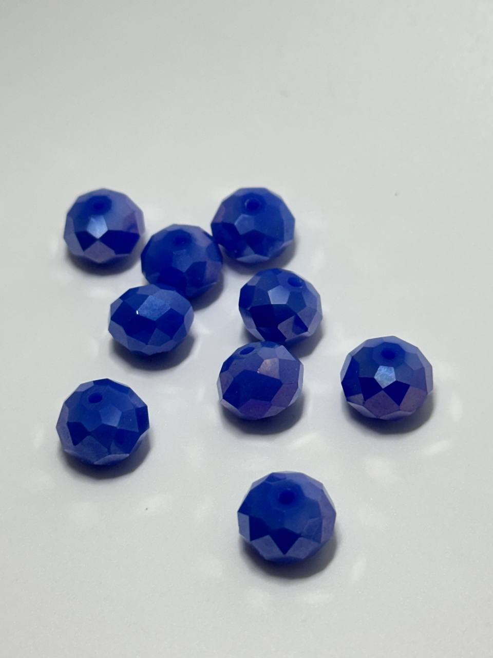 Nine faceted blue beads arranged on a plain white surface.