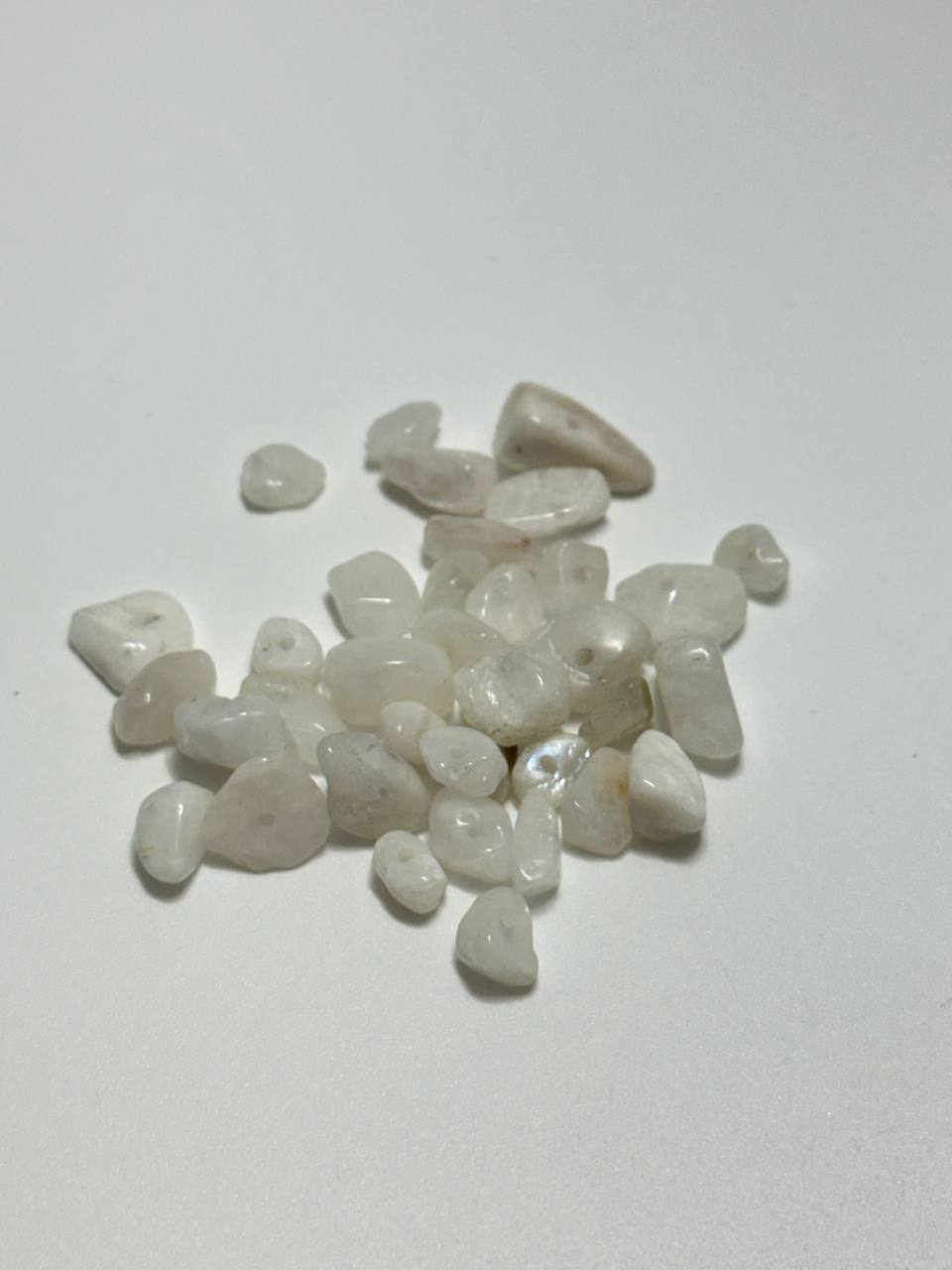 A small pile of milky quartz chip beads on white background