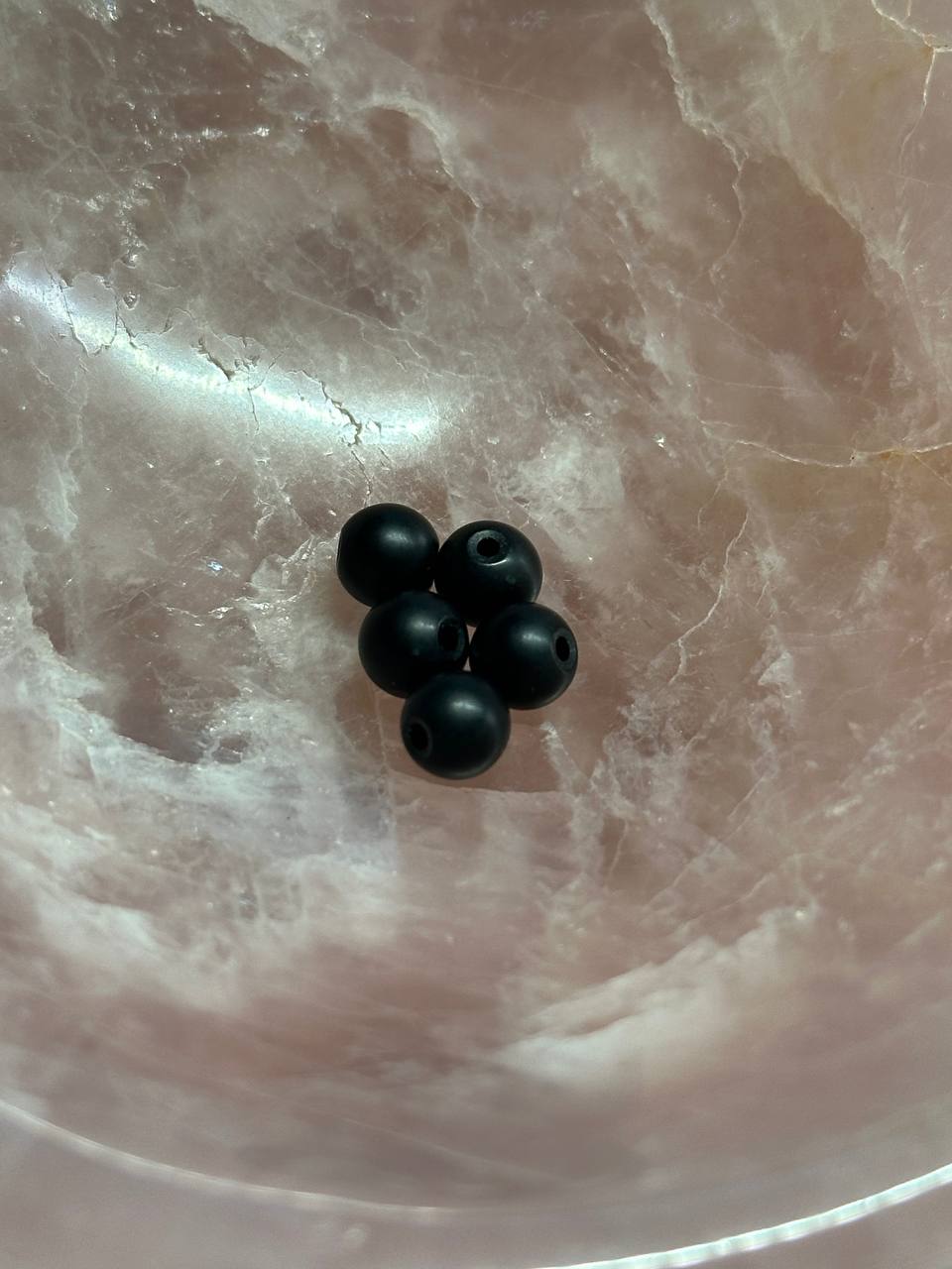 Five black beads on a marbled surface