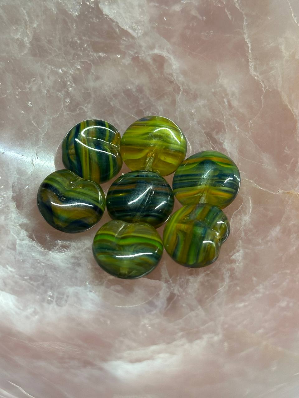 Green marbled stones on a textured pink surface