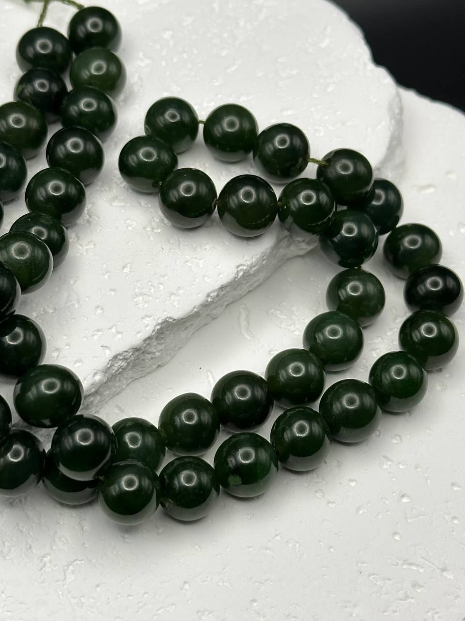 String of dark green beads on a white surface