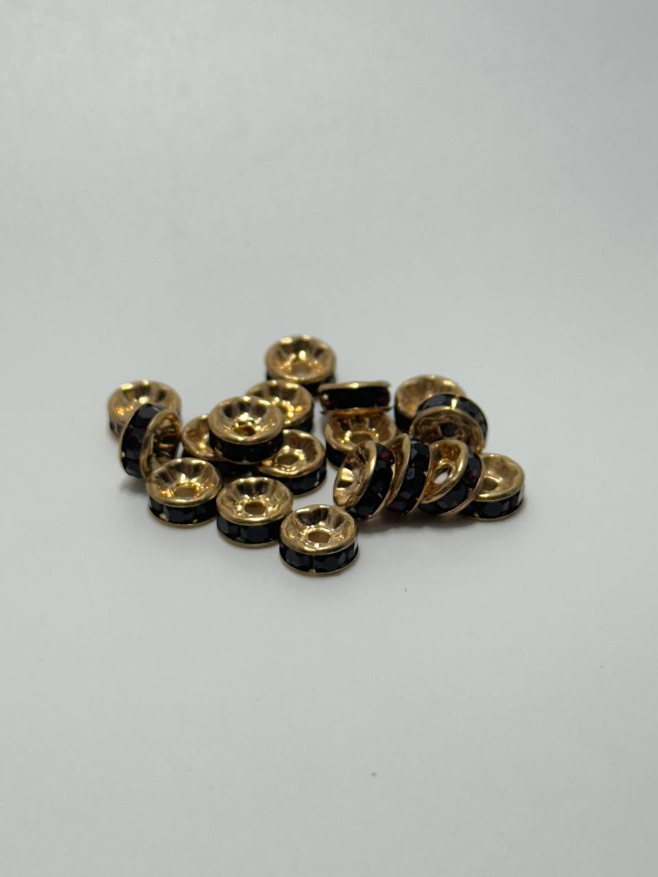 A pile of gold plated brass round spacers with garnet rhinestones