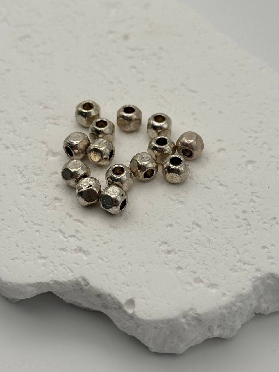 Small silver beads on a textured white surface