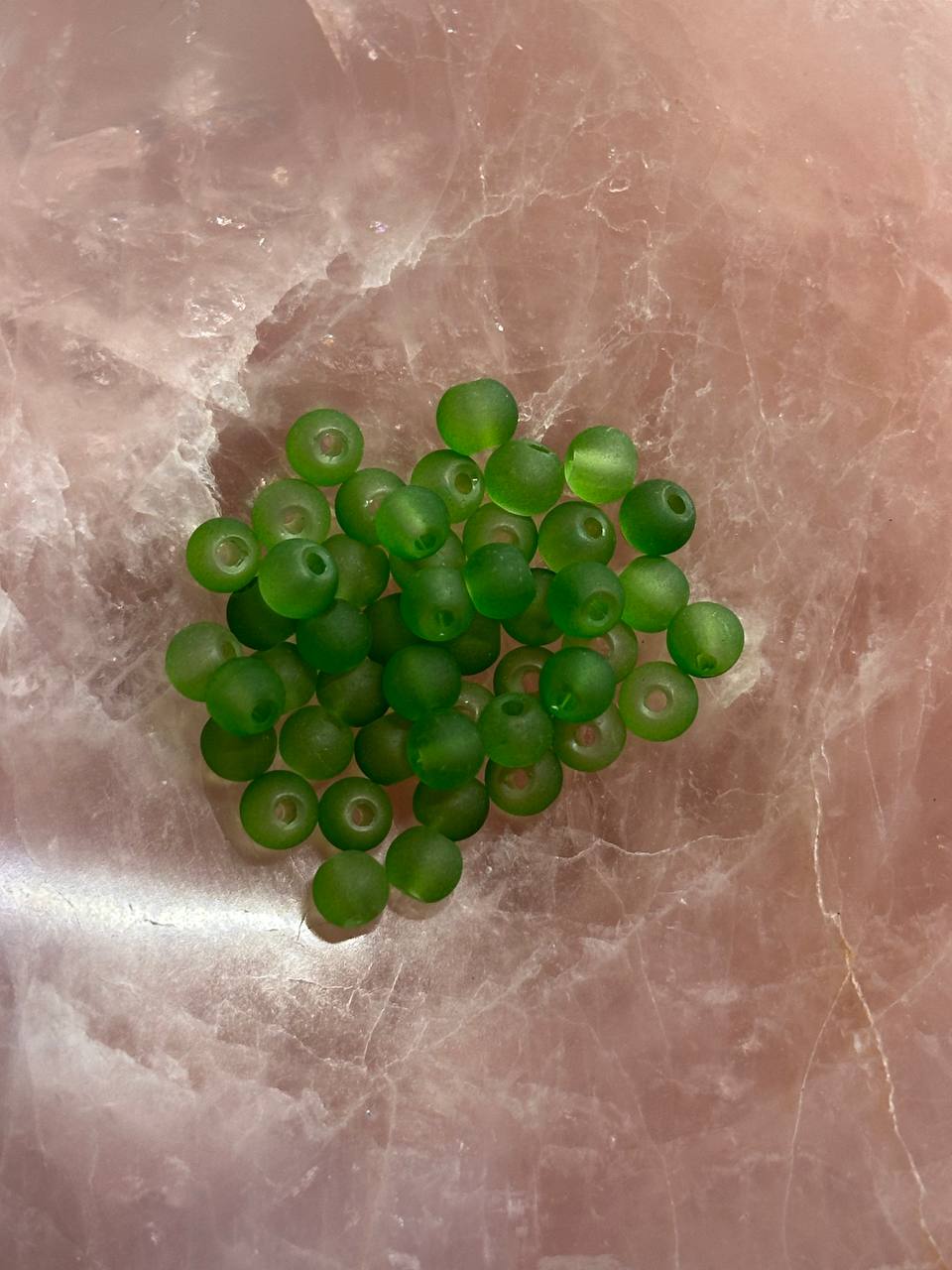 Green druk beads on a marbled surface