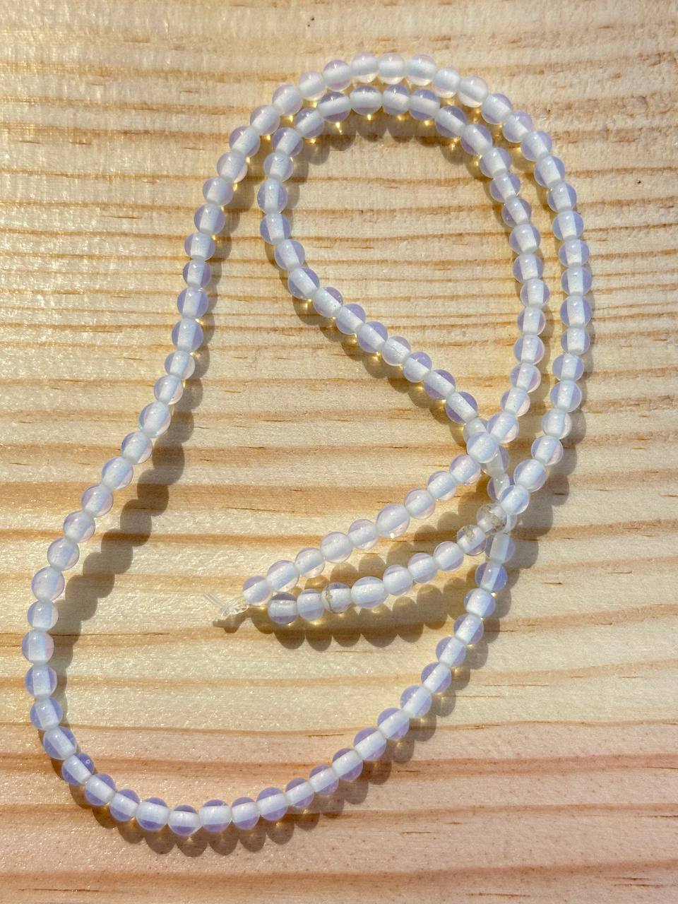 Milky opalite beads on wooden surface