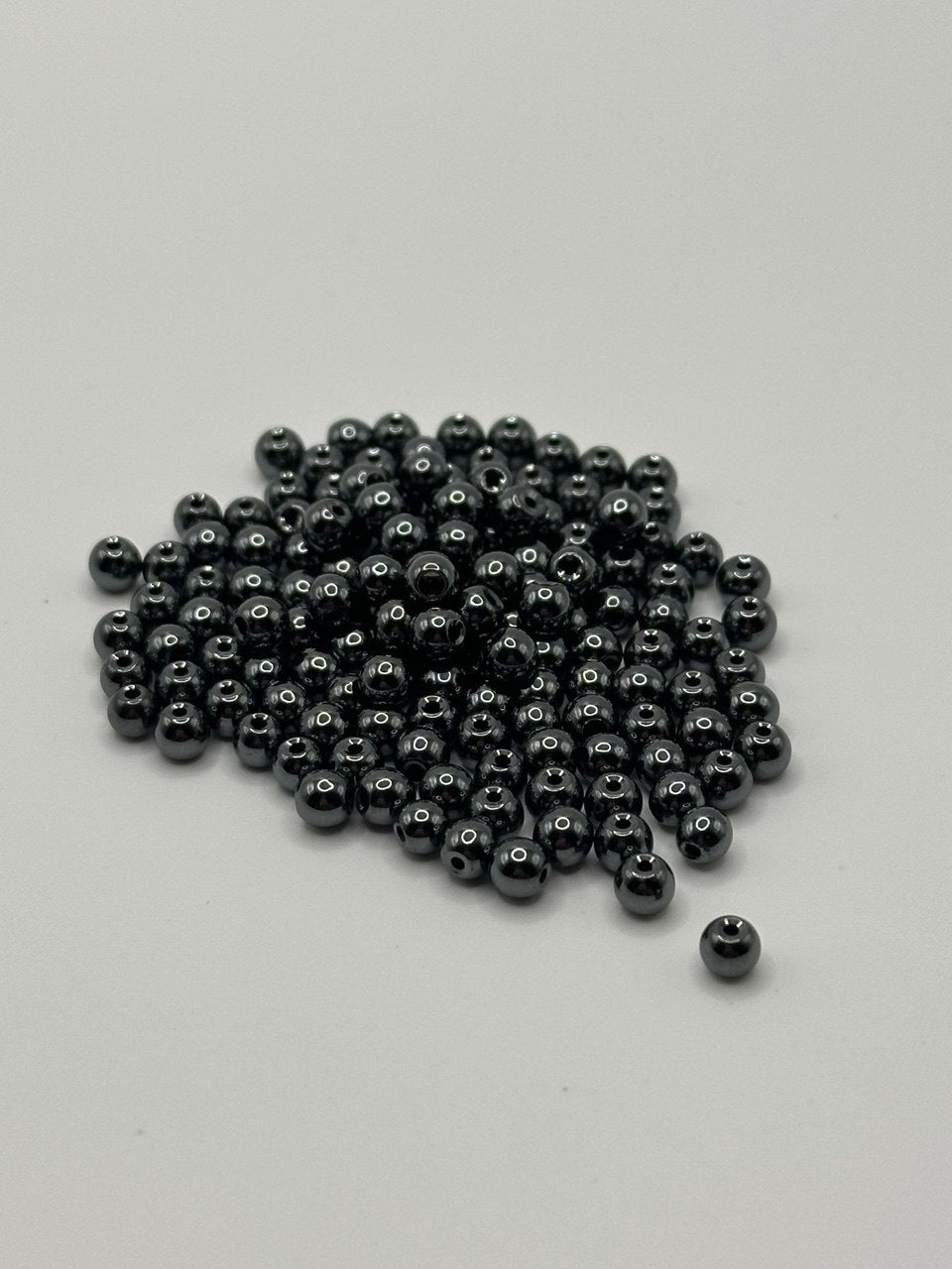 Grey metallic beads scattered on a light gray background