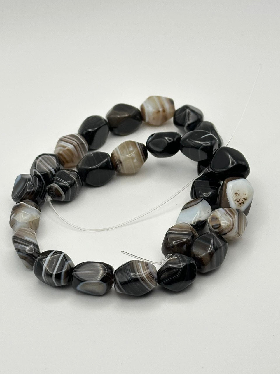 Botswana agate nugget tumbled beads on light grey background