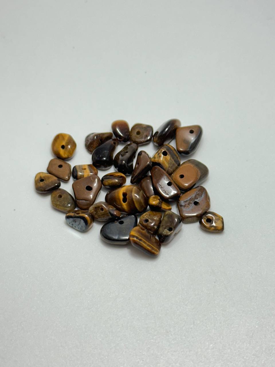 A small pile of tiger's eye chip beads on white background