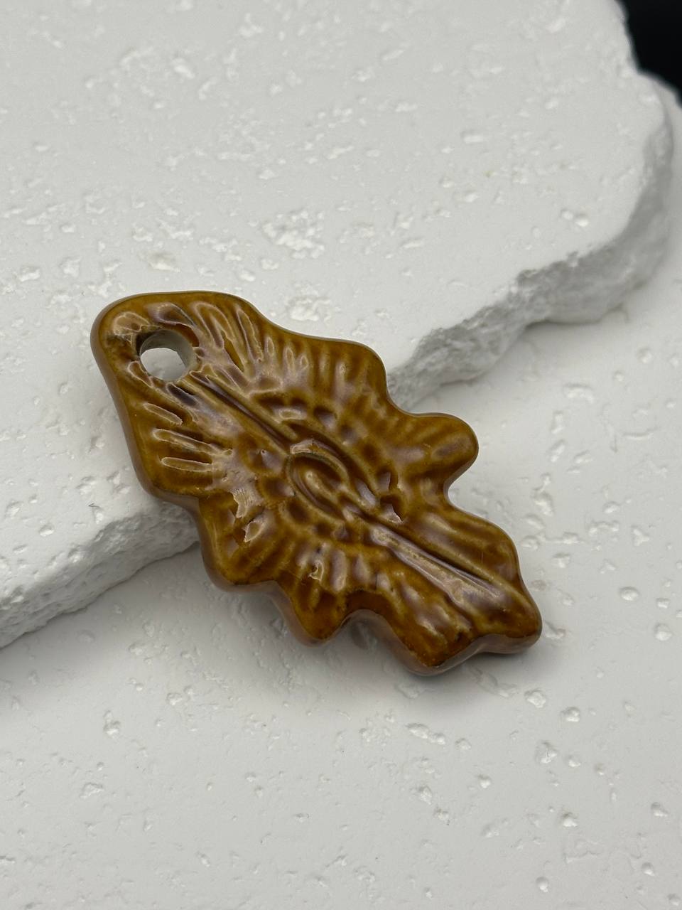 Brown ceramic leaf-shaped object on a textured white surface