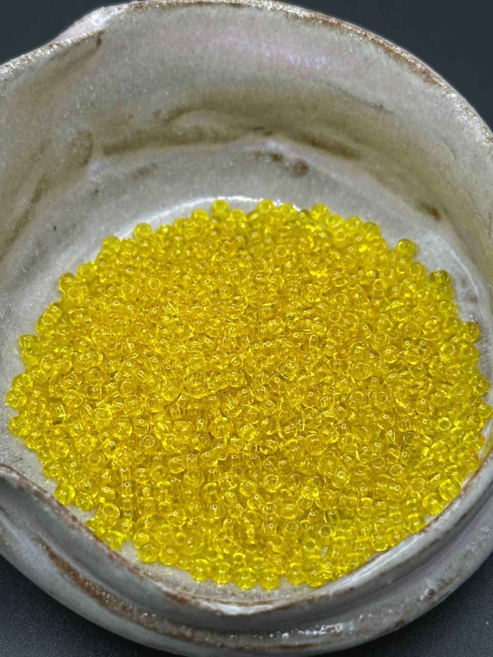 Close-up of yellow beads in a container with a dark background