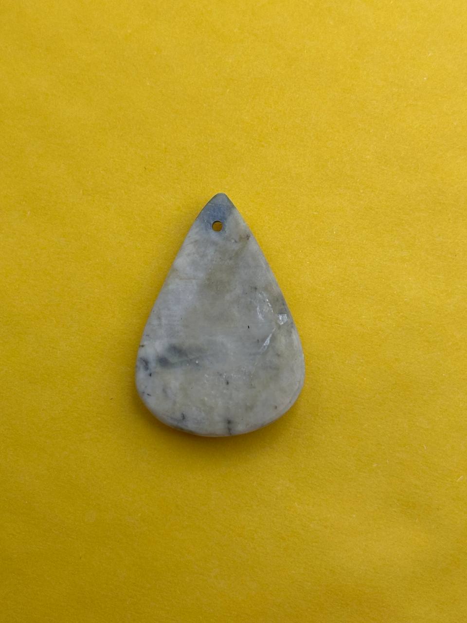 Teardrop-shaped stone pendant on a yellow background