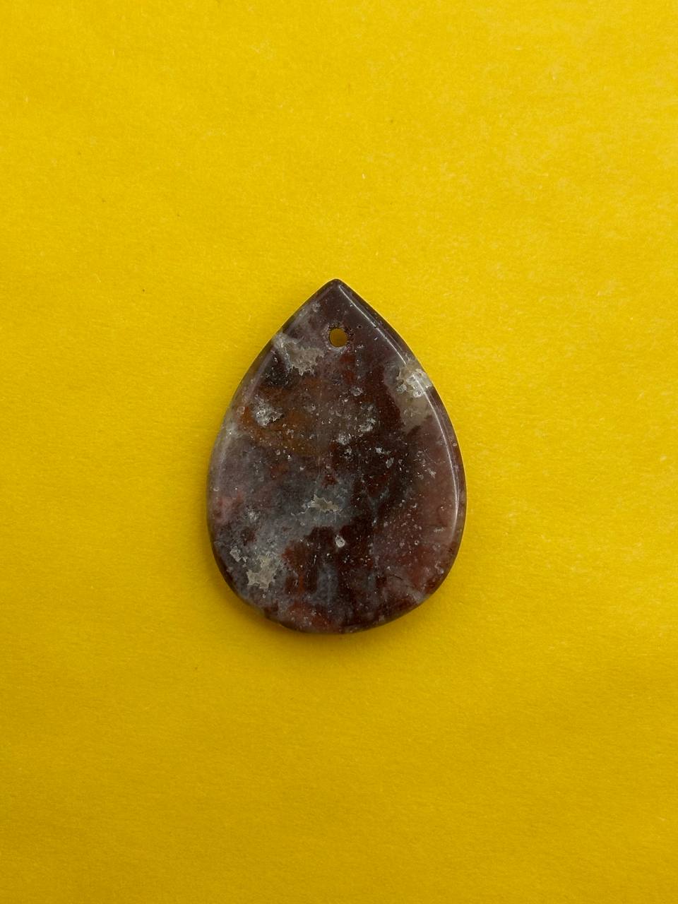 Teardrop-shaped brown stone on a yellow background