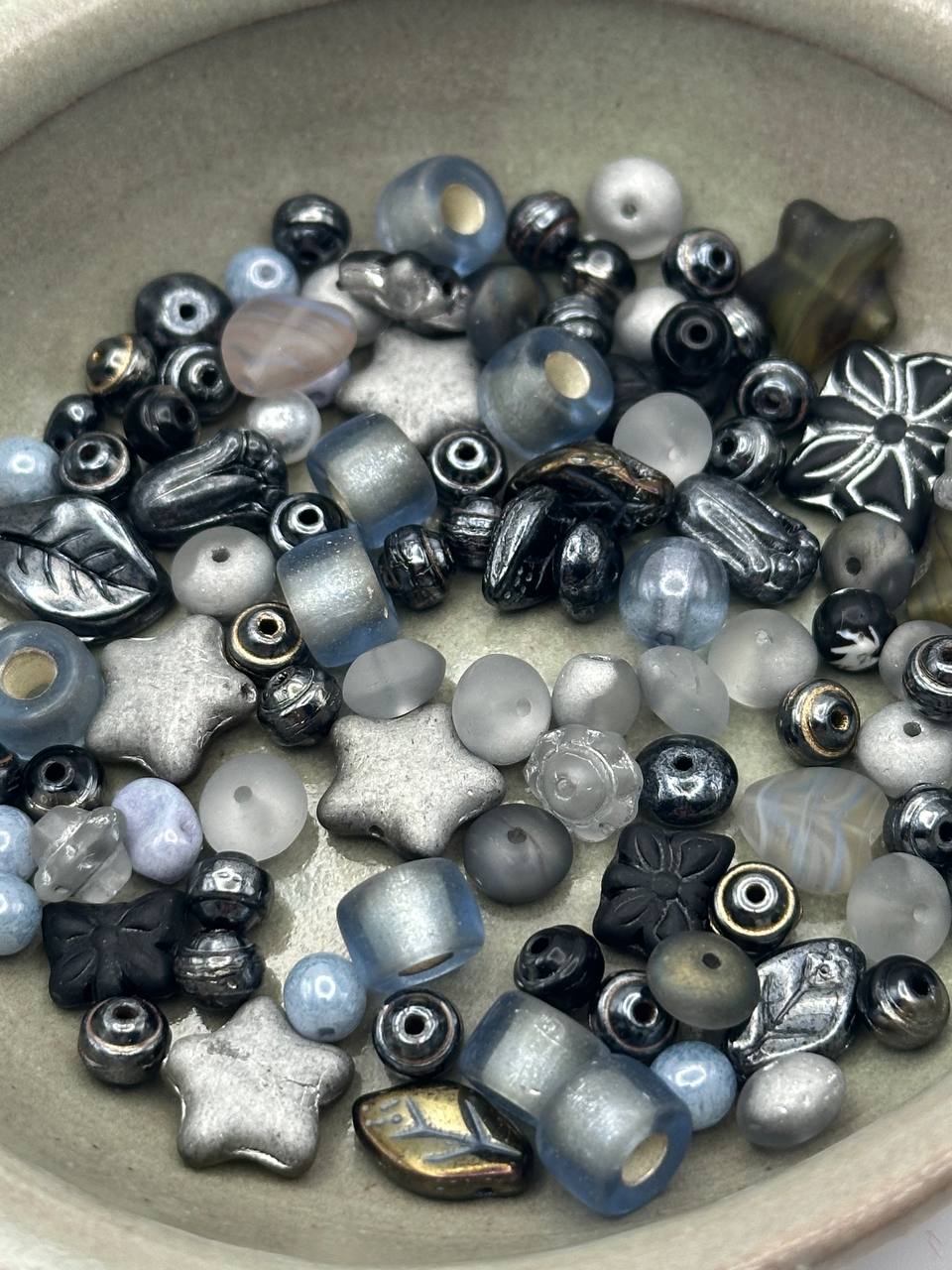 Assorted glass beads in various shapes and colors on a beige surface