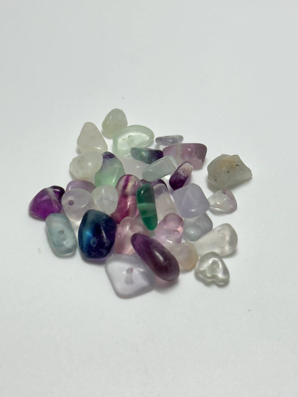A small pile of fluorite chip beads on white background