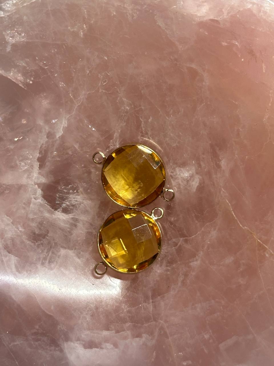 Two yellow pendants on a pink marble surface