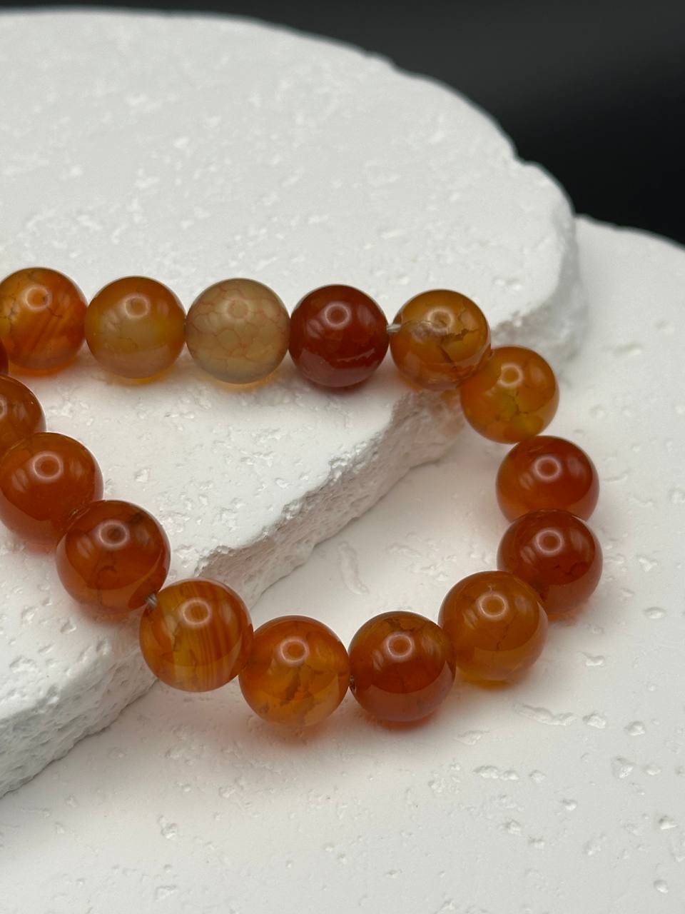 Beaded bracelet with brown and beige beads on a white stone surface