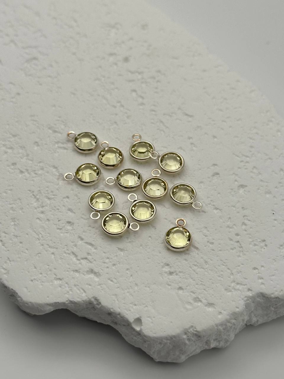 Silver pendants with yellow chatons on a textured stone surface