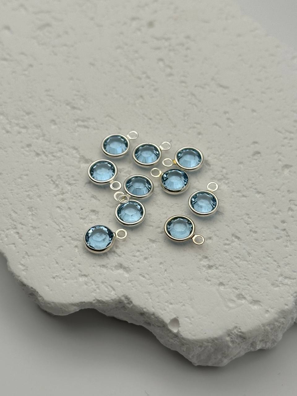 Blue gemstone pendants with silver loops on a textured stone surface