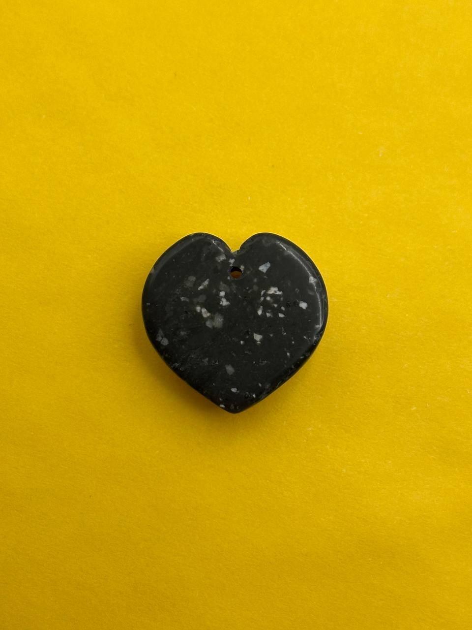 Heart-shaped black stone on a yellow background