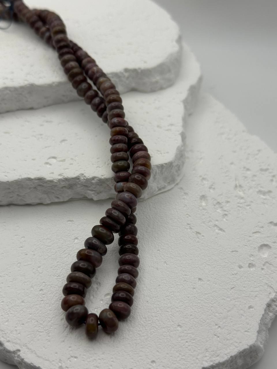 Brown beaded necklace on a textured white surface
