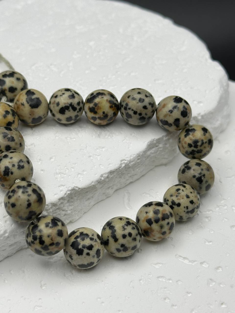 Bracelet with dalmatian stone beads on a white surface