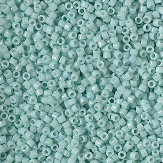 A close-up pile of small cylindrical seed beads in a pale mint green color, filling the entire frame.