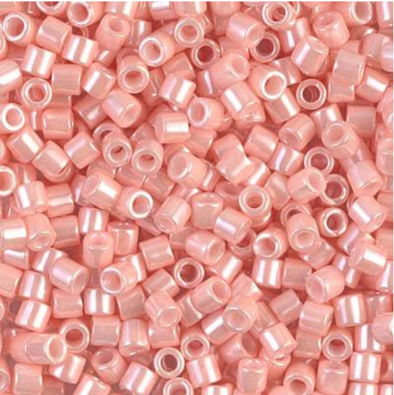A dense pile of small, cylindrical seed beads in a glossy, iridescent light pink color, filling the entire frame.