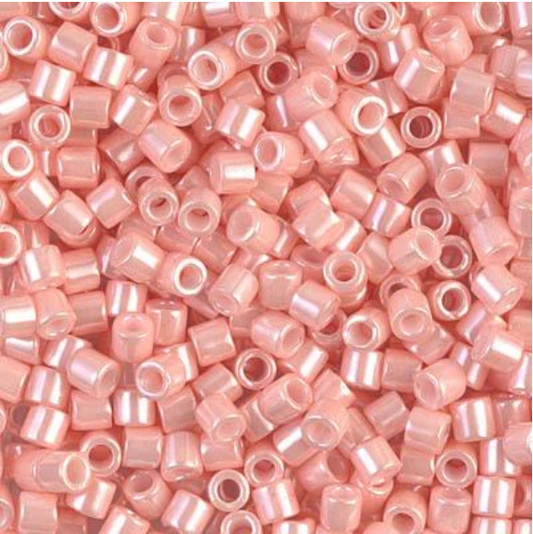A dense pile of small, cylindrical seed beads in a glossy, iridescent light pink color, filling the entire frame.