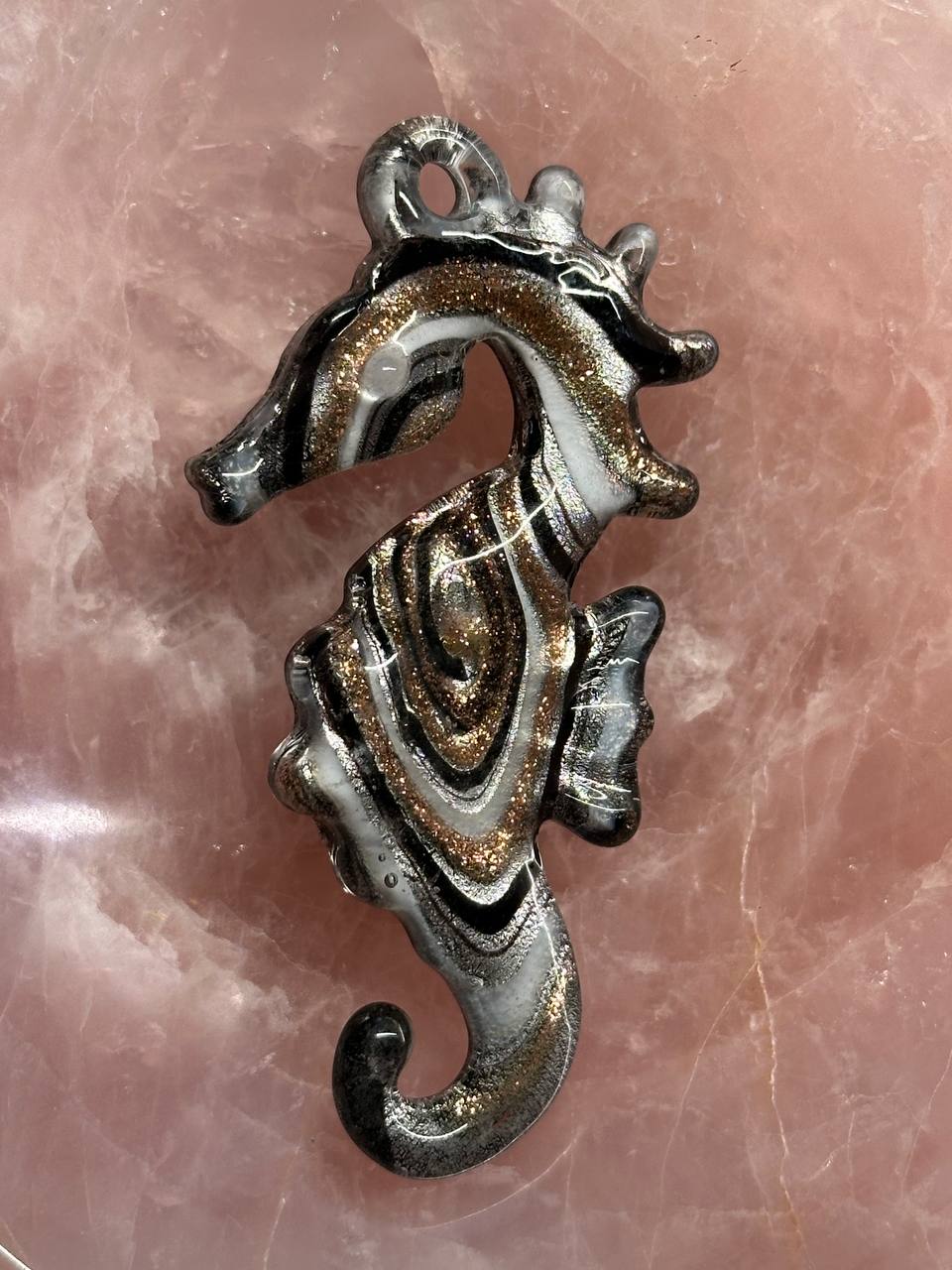 Decorative seahorse pendant on a pink marble background