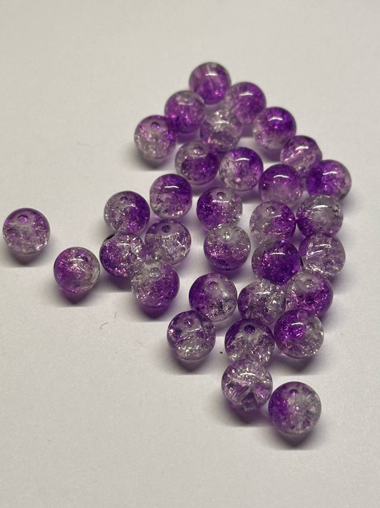 Purple and clear glittery beads on a white background