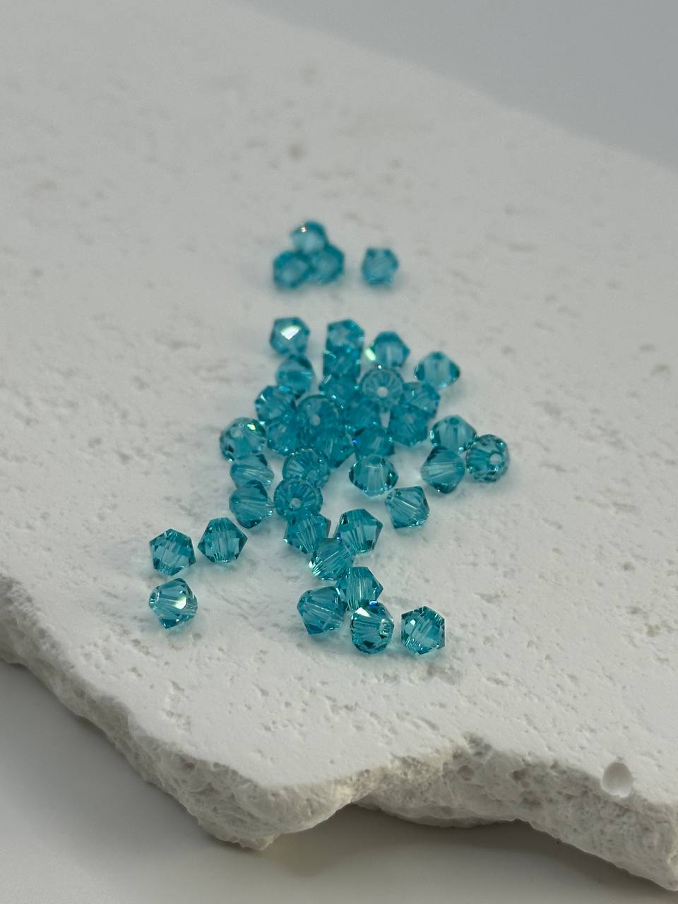 Turquoise bicone beads on a textured white surface
