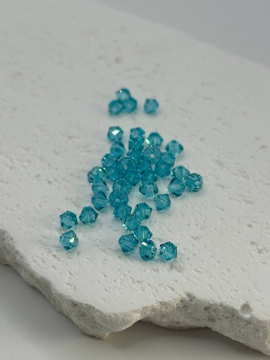 Turquoise bicone beads on a textured white surface